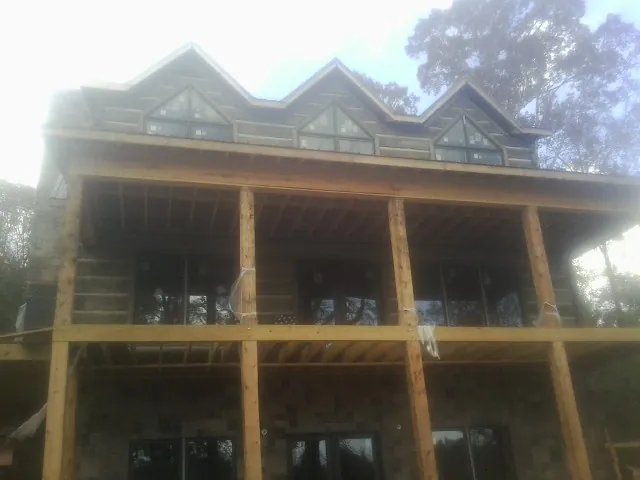 Dormers and porch framing on a large log home under construction — Roof Coating work by our crew in Roscoe