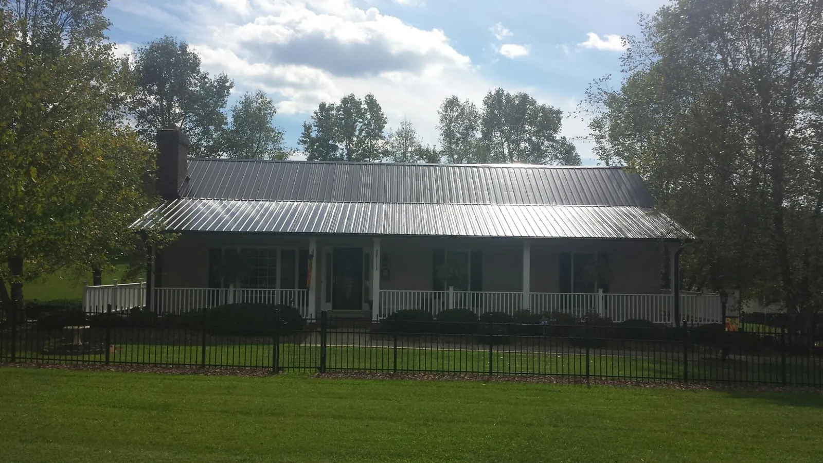 Gray metal roof on a brick ranch with a full width front porch — Gutter Guard Installation work by our crew in Roscoe